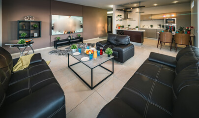 Modern interior of spacious studio apartment. Black leather furniture