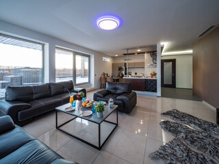 Modern interior of spacious studio apartment. Black leather furniture