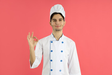 Concept of cooking, young man chef on pink background