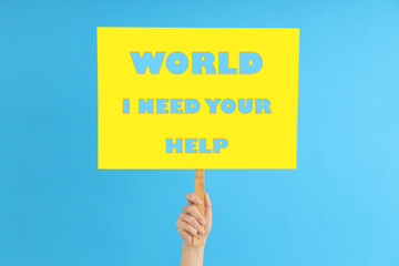 Female hand holds protest sign with text World I need your help on blue background