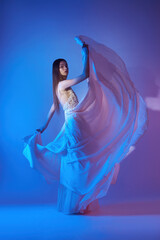 Art beautiful woman in blowing flying dress. Freedom concept in neon color light. Fashion style of flowing dress on body woman. Flying Dress Fluttering on Wind