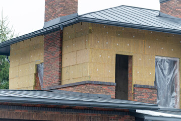 Insulation of brickwork with mineral wool. Thermal insulation of a house wall on a building site