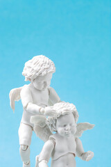 Angels baby figurine on blue background. Funny flying cherubs sculpture