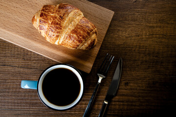 Croissant with a cup of full coffee, directly above	
