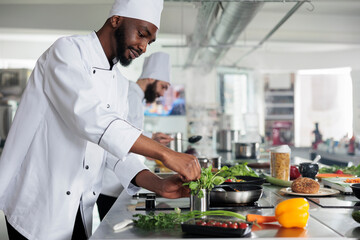 African american professional head chef picking fresh green herbs to improve gourmet dish taste....