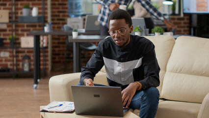 Business man attending online work teleconference in office, using laptop with webcam. Male employee talking to people on remote videoconference call for telecommunication sales.