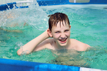 Fototapeta na wymiar Happy boy splashing on summer pool having fun leisure activity