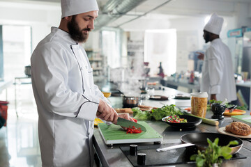Caucasian food industry worker chopping organic and fresh red pepper while cooking delicious food for dinner service at restaurant. Master chef cutting vegetables in professional kitchen.