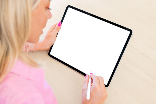 Woman using tablet computer with stylus pen, empty white screen mockup, over the shoulder view