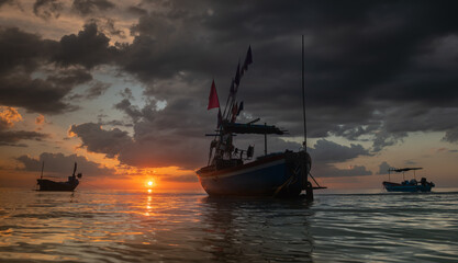 Silhouette fishery boats in the sea with sunset lighting.