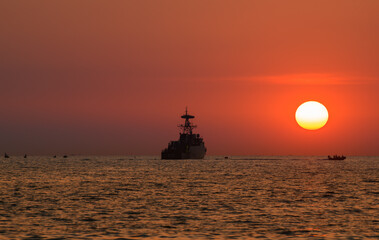Silhouette military war ship and the sun.