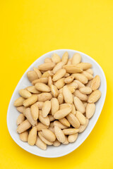 clean almonds on small white dish on yellow