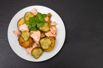 fresh baked salmon with fried potato and cucumber on plate