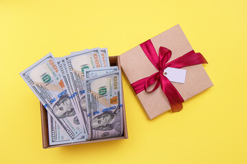gift box filled with money, next to it is a lid tied with a satin ribbon and with an empty tag