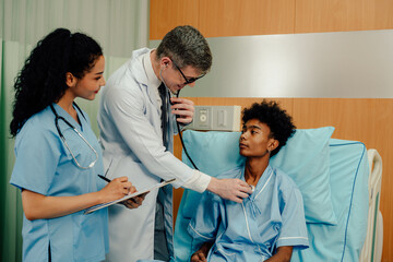 Obraz premium Young patient man sitting in bed while doctor checking his pulse. Doctor examining senior male patient in hospital room.