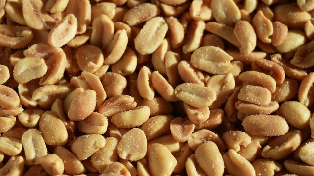 Close-up view 4k stock video footage of many crispy tasty salted roasted peeled peanuts for background. Nuts spinning around slowly
