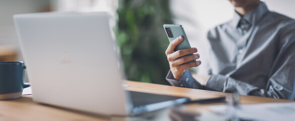 Young man working with laptop and smartphone in the office.