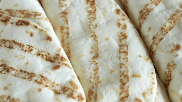 Close-up top view 4k stock video footage of tasty tortilla wraps stuffed with juicy meat with sauce. Wrapped sandwiches with grilled vegetables and meat pieces