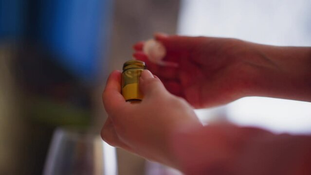 Woman opens and examine small brown bottle of poisonous powder ready to poison relative and get heritage at dinner at home closeup slow motion