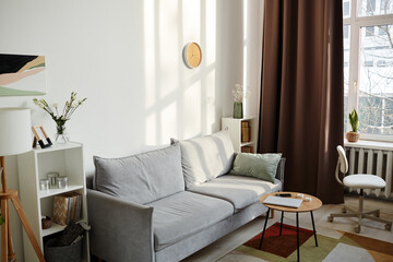Sunlit background image of cozy living room interior with comfy velvet couch and minimal decor lit by sunlight, copy space