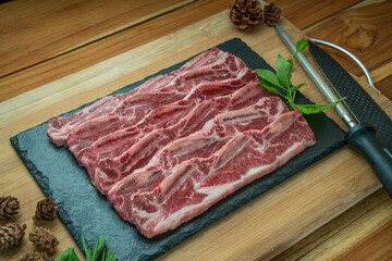 Beef Short Ribs (Sliced) Bone-in on wooden background.Cross Cut Short Ribs beef on black plate. 