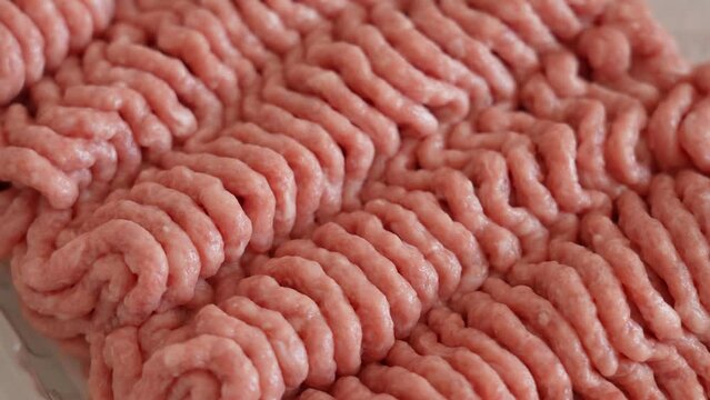 Closeup view 4k video footage of fresh raw minced or grounded organic turkey meat isolated in white plastic package spinning around slowly. Pink and white meat  ingridients texture