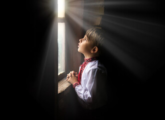 Small boy praying at the window