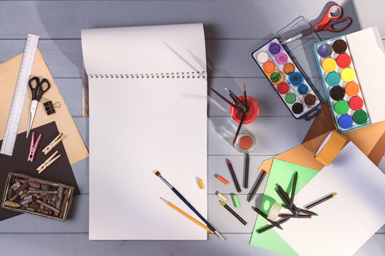 Drawing in art studio top view. Blank paper mock-up on gray wooden table or floor background. Flat lay creative concept image