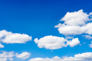 Obraz na płótnie Canvas Beautiful white fluffy clouds slowly float against the blue sky on a warm sunny summer day.