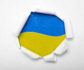 Ukrainian blue and yellow flag in the round hole in paper