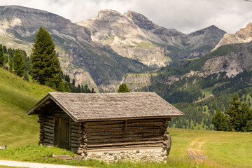Fototapeta na wymiar Small wooden cabin with mountains in the background in Val Gardena. South Tyrol