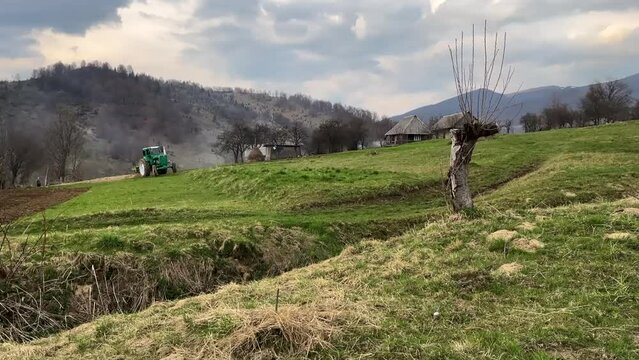 Tractor in the mountains plows the field. Village in the mountains. 