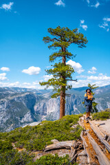 A young man with a brown jacket in Sentinel Dome looking at Upper Yosemite Fall, Yosemite National Park. United States