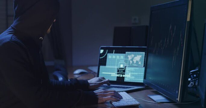 Hacker does digital machinations on online stock exchange in office side view. Cyber criminal attacks global companies financial actives - Powered by Adobe