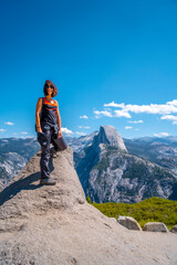 A young woman in pink and black at the Glacier point on the Half Dome wall. Yosemite National Park, United States