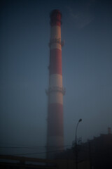 Pipe of plant is in fog. View of industrial area in morning. Haze in metropolis. Environmental pollution.
