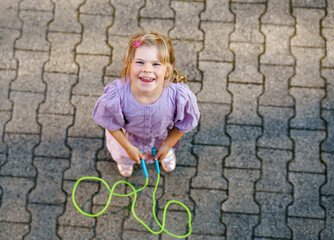 Little preschool girl jump and train with skipping rope. View from above on cute happy active...