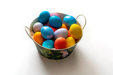 Naklejka na ściany i meble multi-colored easter eggs in a basket on a white background