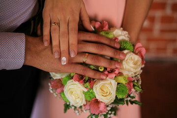 Obraz na płótnie Canvas Touching hands of groom and bride near bouquet of flowers. Wedding day concept. Wedding picture. Love is.
