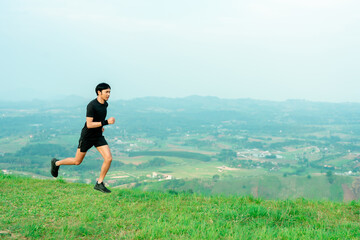 Obraz premium Portrait of an Asian male trail runner running. On the high mountains there are beautiful views. It's a trail running practice. on a bright day Behind is a beautiful mountain view.