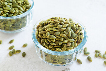pumpkin seeds in glass bowl on white marble table background.