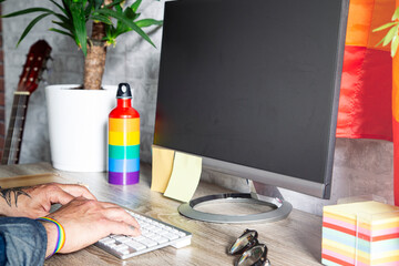 The hands of the man who works in the office with LGBT accessories.