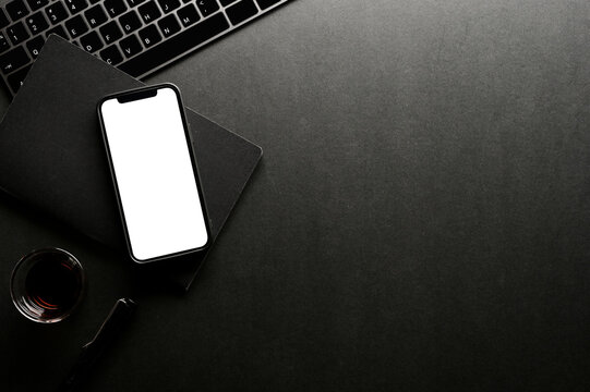 Dark office desk with smartphone mockup, office accessories and copy space.