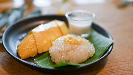 Mango with sticky rice on a black plate. Asian desserts.