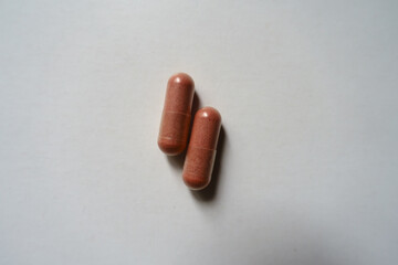 Close shot of two pink capsules of PQQ dietary supplement