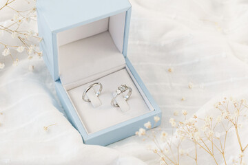 Wedding and engagement rings in a blue box set against a white background. Wedding concept image with copy space available
