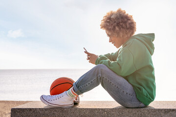smiling woman using her phone sitting on a bench