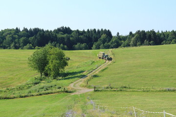 Tractor driving hay fresh bale on the field.