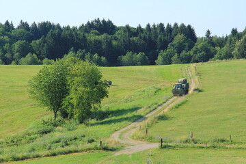 Fototapeta na wymiar Tractor driving hay fresh bale on the field.