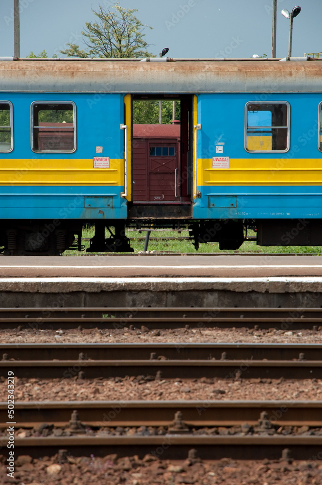 Poster Abandoned blue and yellow train carriage and railway tracks